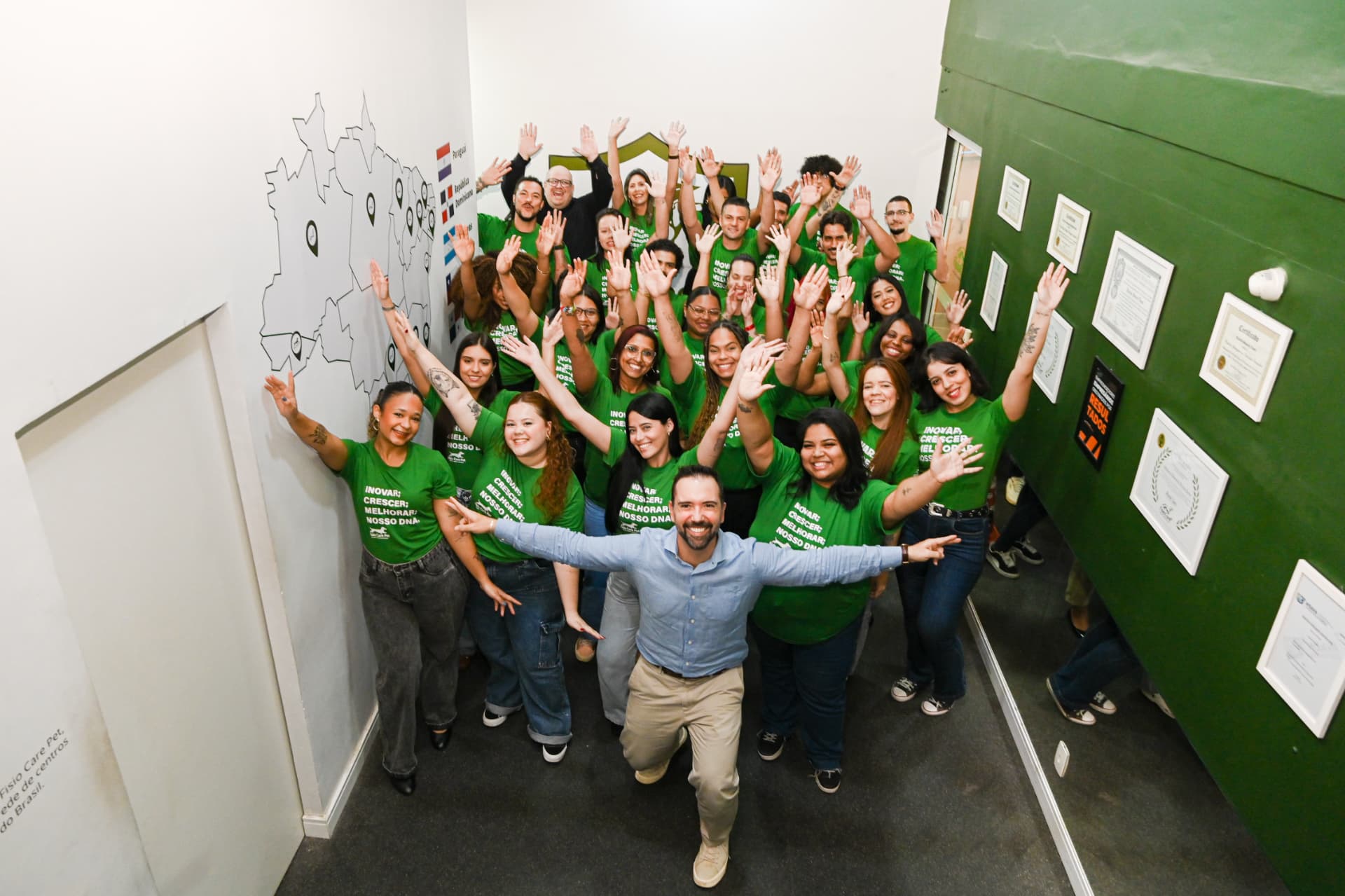 Turma e equipe da Fisio Care Pet reunidas na unidade com os braços levantados